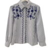 Blusa de algodón con rayas verticales azul marino y bordados florales en azul intenso, detalle geométrico en zigzag y puños