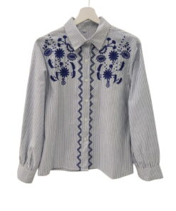 Blusa de algodón con rayas verticales azul marino y bordados florales en azul intenso, detalle geométrico en zigzag y puños