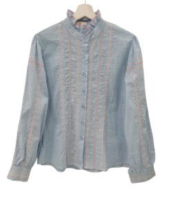 Blusa azul claro de manga larga para chica, con cuello alto de volantes y bordados de flores en tonos rosados y blancos en la