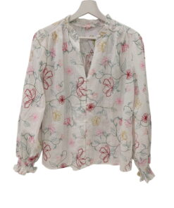 Blusa blanca de chica con flores de colores bordadas, corte holgado, mangas largas abullonadas y cuello en V con borde fruncí