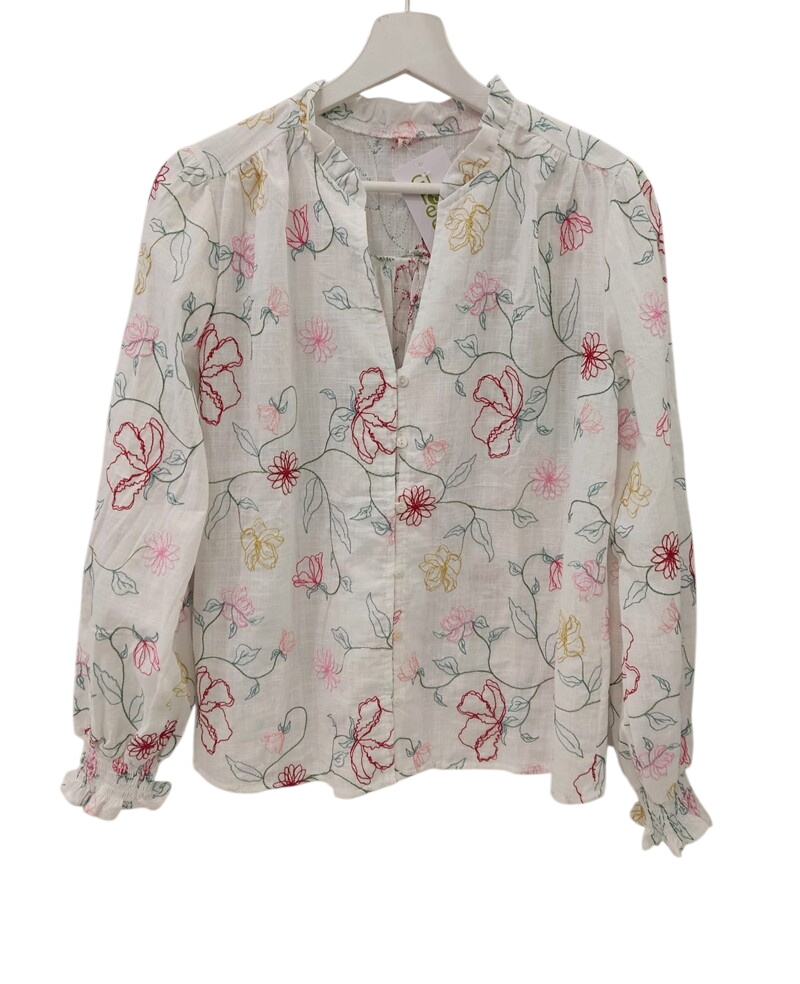 Blusa blanca de chica con flores de colores bordadas, corte holgado, mangas largas abullonadas y cuello en V con borde fruncí