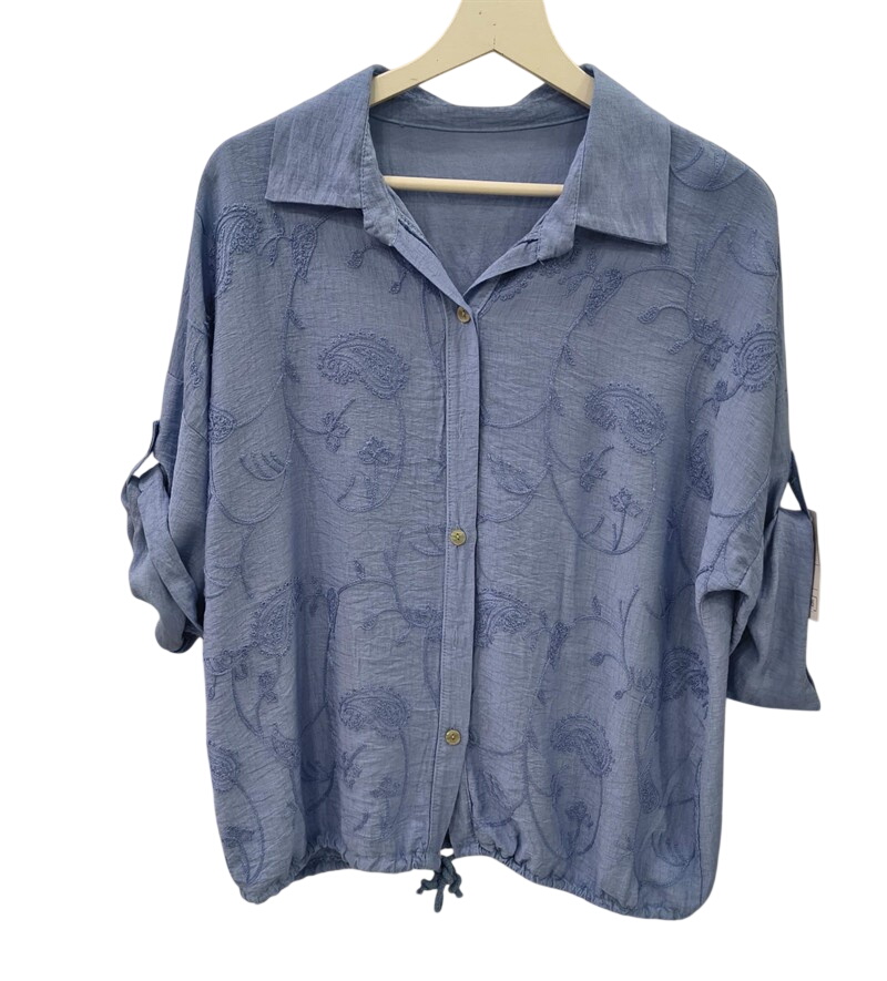 Blusa de manga larga en tono azul celeste oscuro con bordados de paisley, cuello clásico, botones frontales y dobladillo con