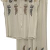 Conjunto de chica en color crema con blusa holgada y pantalón ancho, ambos con bordados florales marrones, azules y dorados