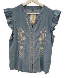 Blusa vaquera sin mangas en azul denim para chica, con bordados florales crema a ambos lados y volantes decorativos en las sI