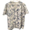 Camisa de chica con estampado tropical de hojas de palma azul, fondo claro, manga corta, algodón ligero. Corte recto y cuello