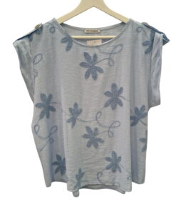 Blusa azul claro de corte holgado para chica, cuello redondo amplio, bordados de flores y hojas azul oscuro, mangas caídas