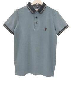 Polo de chico en azul grisáceo liso, manga corta, corte recto, cuello polo negro con detalles blancos y pequeño escudo bordad