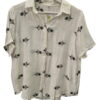 Camisa de manga corta para chica en color blanco, corte holgado, con flores bordadas negras sobre fondo claro y cuello de sol