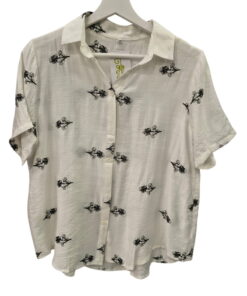 Camisa de manga corta para chica en color blanco, corte holgado, con flores bordadas negras sobre fondo claro y cuello de sol