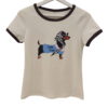 Camiseta de chica en tono crema con cuello redondo marrón, manga corta y estampado central de perro salchicha con pañuelo y l