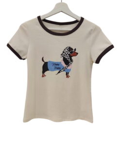 Camiseta de chica en tono crema con cuello redondo marrón, manga corta y estampado central de perro salchicha con pañuelo y l