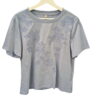 Camiseta de chica azul grisáceo de manga corta, cuello redondo y flores bordadas en relieve en el frontal, tejido de algodón