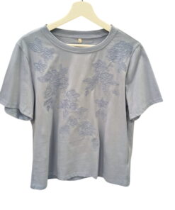 Camiseta de chica azul grisáceo de manga corta, cuello redondo y flores bordadas en relieve en el frontal, tejido de algodón