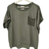 Blusa de chica en tejido verde oliva, corte holgado, con ganchillo en hombros y bolsillo en el pecho. Detalle de dobladillo y