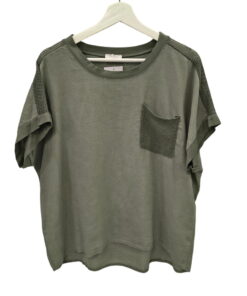 Blusa de chica en tejido verde oliva, corte holgado, con ganchillo en hombros y bolsillo en el pecho. Detalle de dobladillo y
