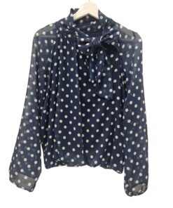 Blusa de gasa azul marino con estampado de lunares blancos para chica, cuello alto con lazo, manga larga y bajos elásticos. A