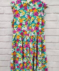 Vestido corto camisero estampado de flores, con cierre de botones. Sin mangas y con volante en la sisa.