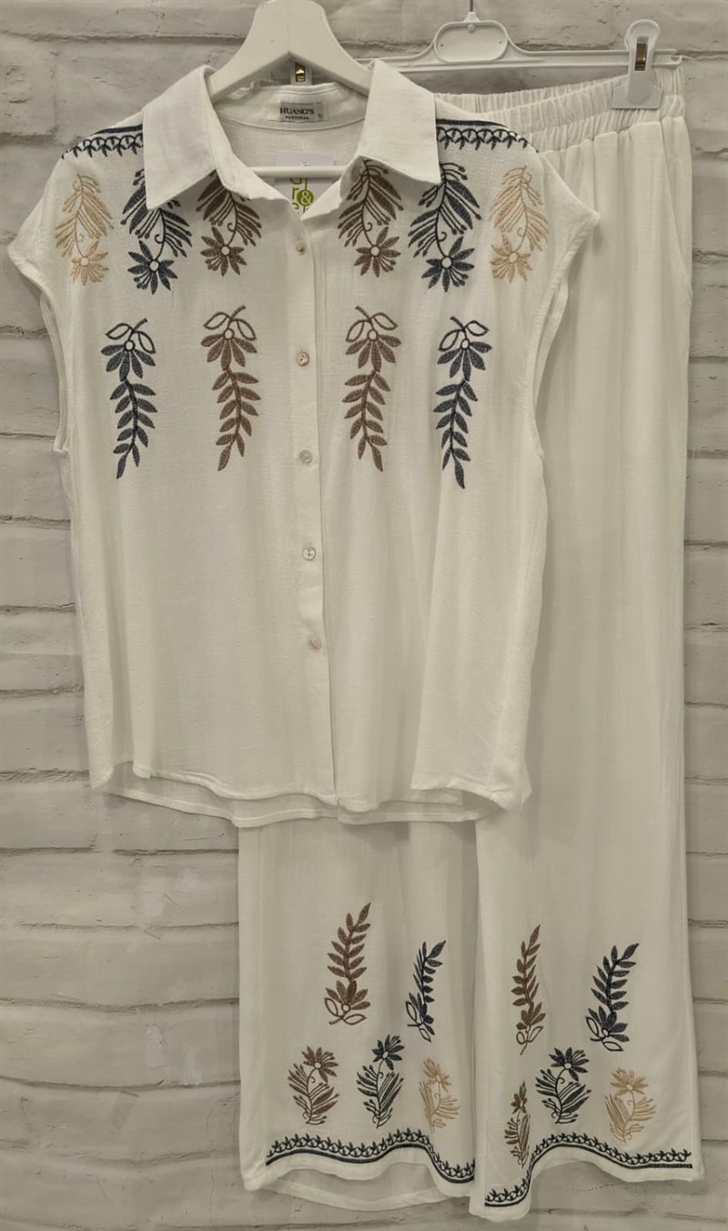 Conjunto de chica en color crema con blusa holgada y pantalón ancho, ambos con bordados florales marrones, azules y dorados