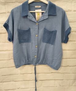 Camisa azul grisáceo para chica con cuello de ganchillo oscuro, mangas cortas también bordeadas en ganchillo, bolsillos front
